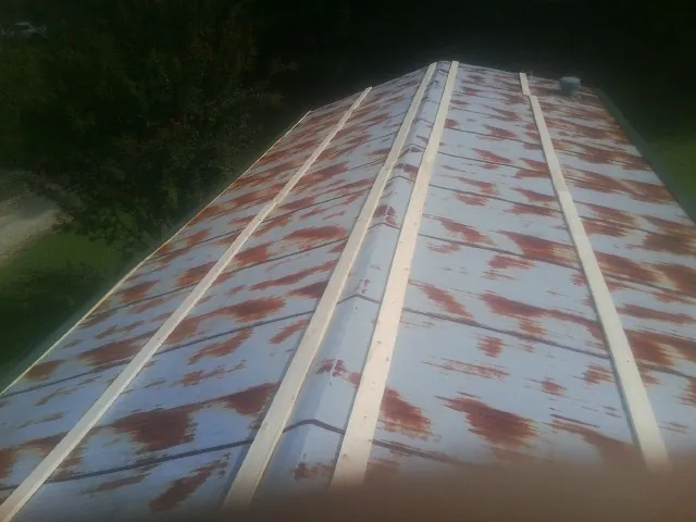 Rusted metal roof panels with new wood purlins before replacement in Climax