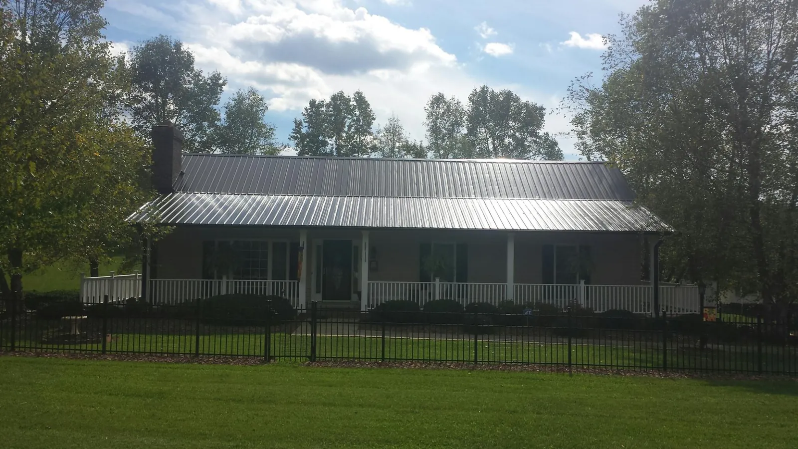 Gray metal roof on a brick ranch with a full width front porch — Gutter Guard Installation work by our crew in Climax