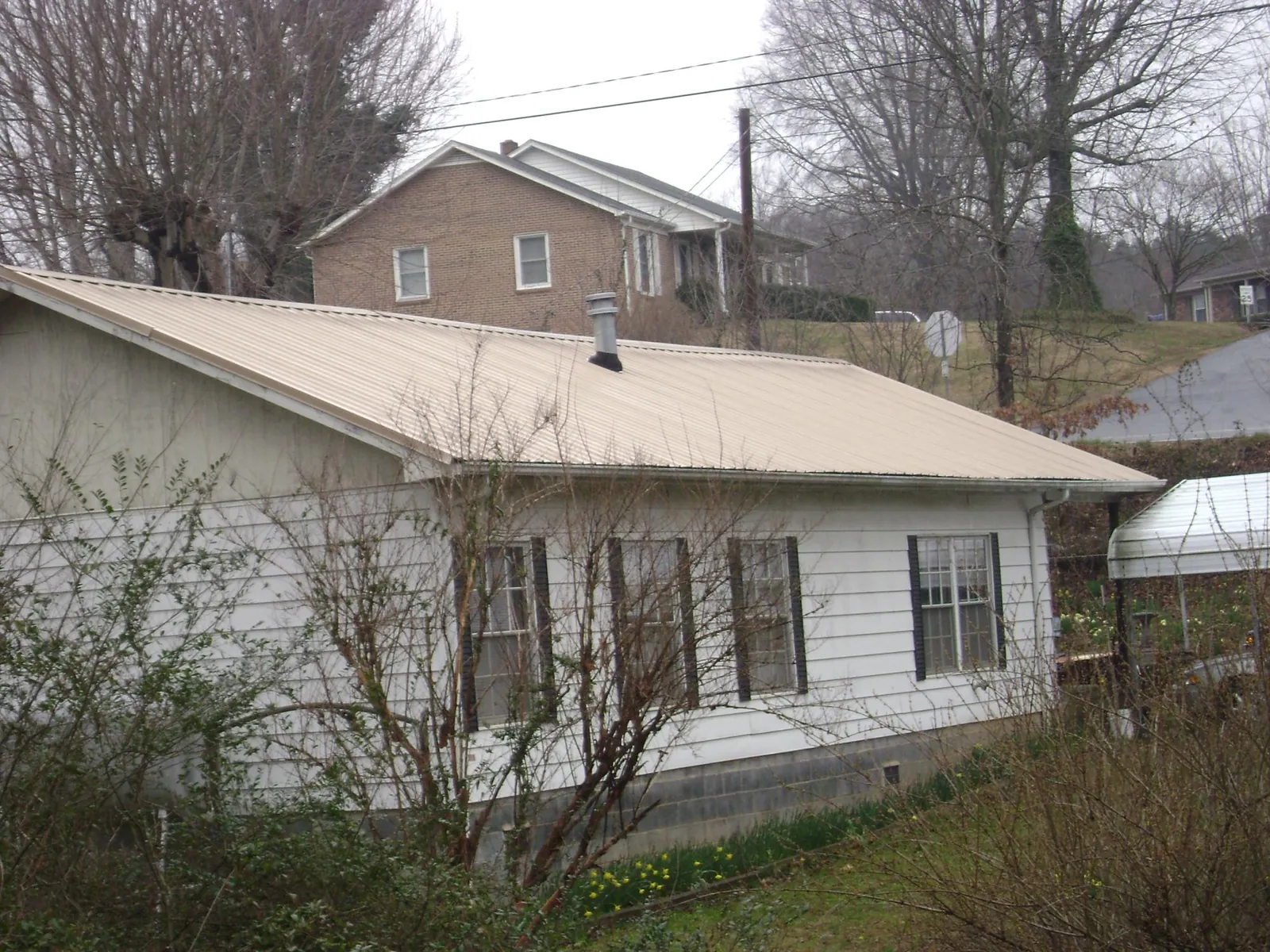 Tan metal roof on a white sided house set into a hillside — Commercial Roofing by Roofing Brothers in Climax